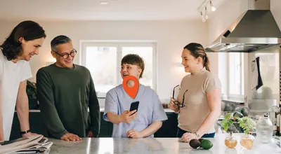 A family gathered around a smartphone in a kitchen