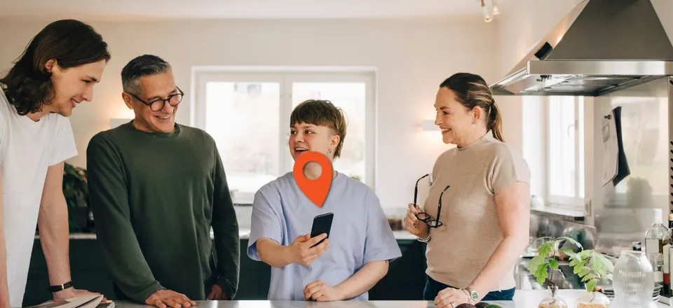 A family gathered around a smartphone in a kitchen