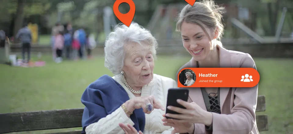 An elderly woman and her adult daughter looking at the Device Tracker Plus app together on a park bench