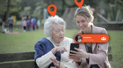 An older woman being introduced to the Device Tracker Plus app on a bench in a park
