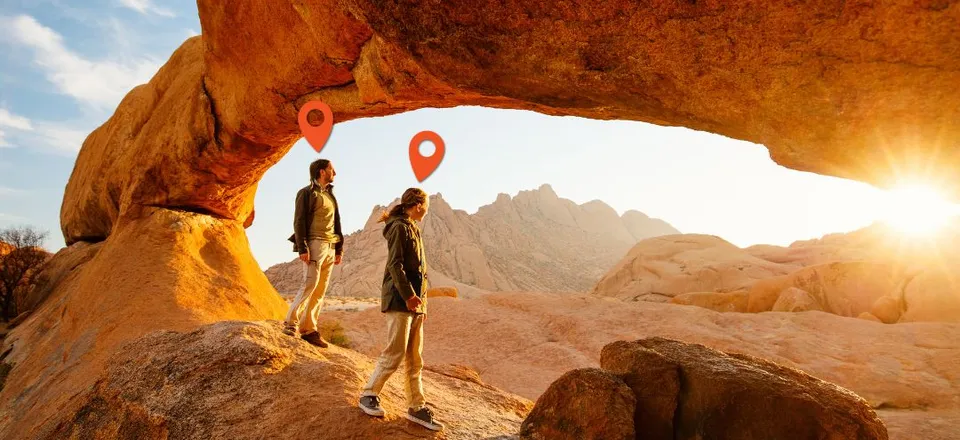Two people watching a sunset in a rocky desert landscape