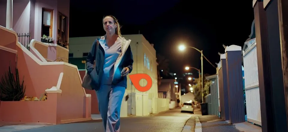 A female medical worker walking alone down a city street at night
